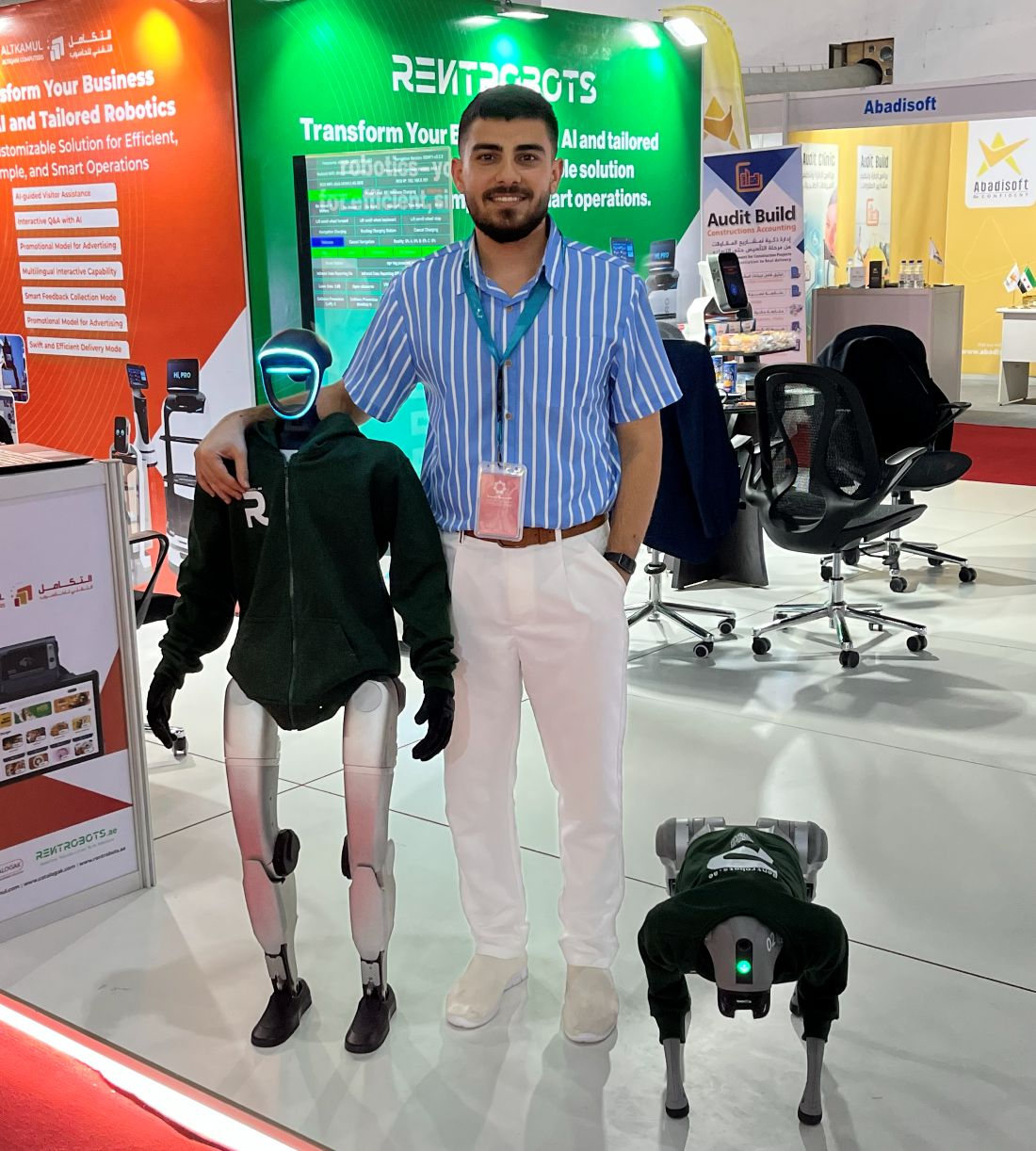 Yazan Mohamed on the Al Takamul stand with a humanoid service robot and a quadruped robot