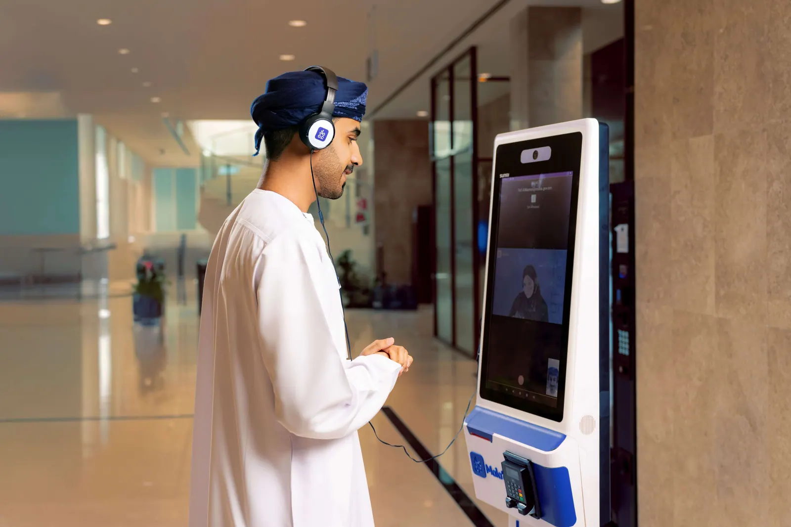 A visitor on a video call with customer service at a Mala’a self-service kiosk