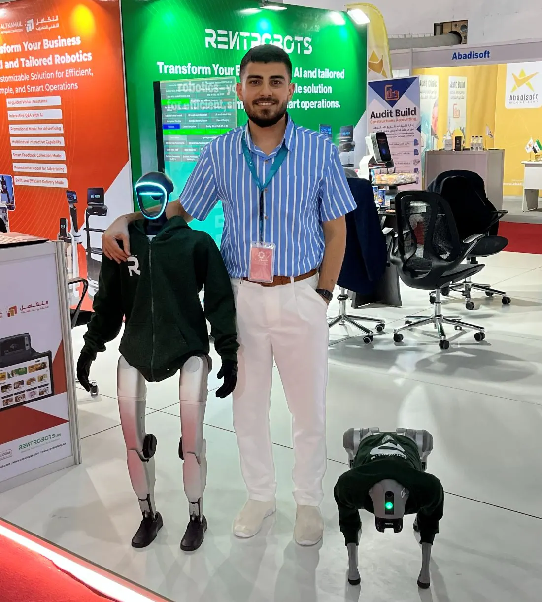 Yazan Mohamed on the Al Takamul stand with a humanoid service robot and a quadruped robot